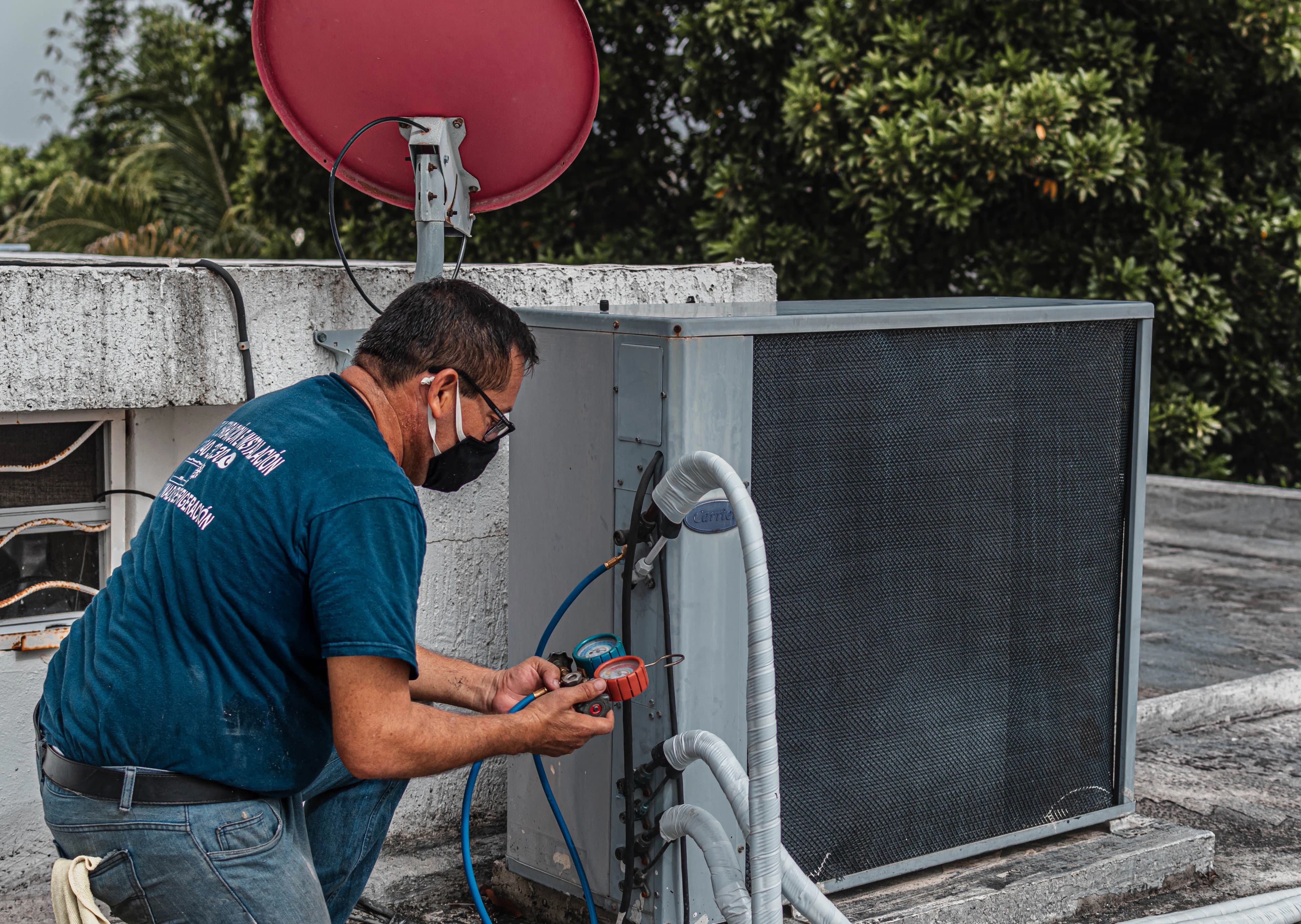 Technician reading refrigerant gauges at an air conditioning unit
