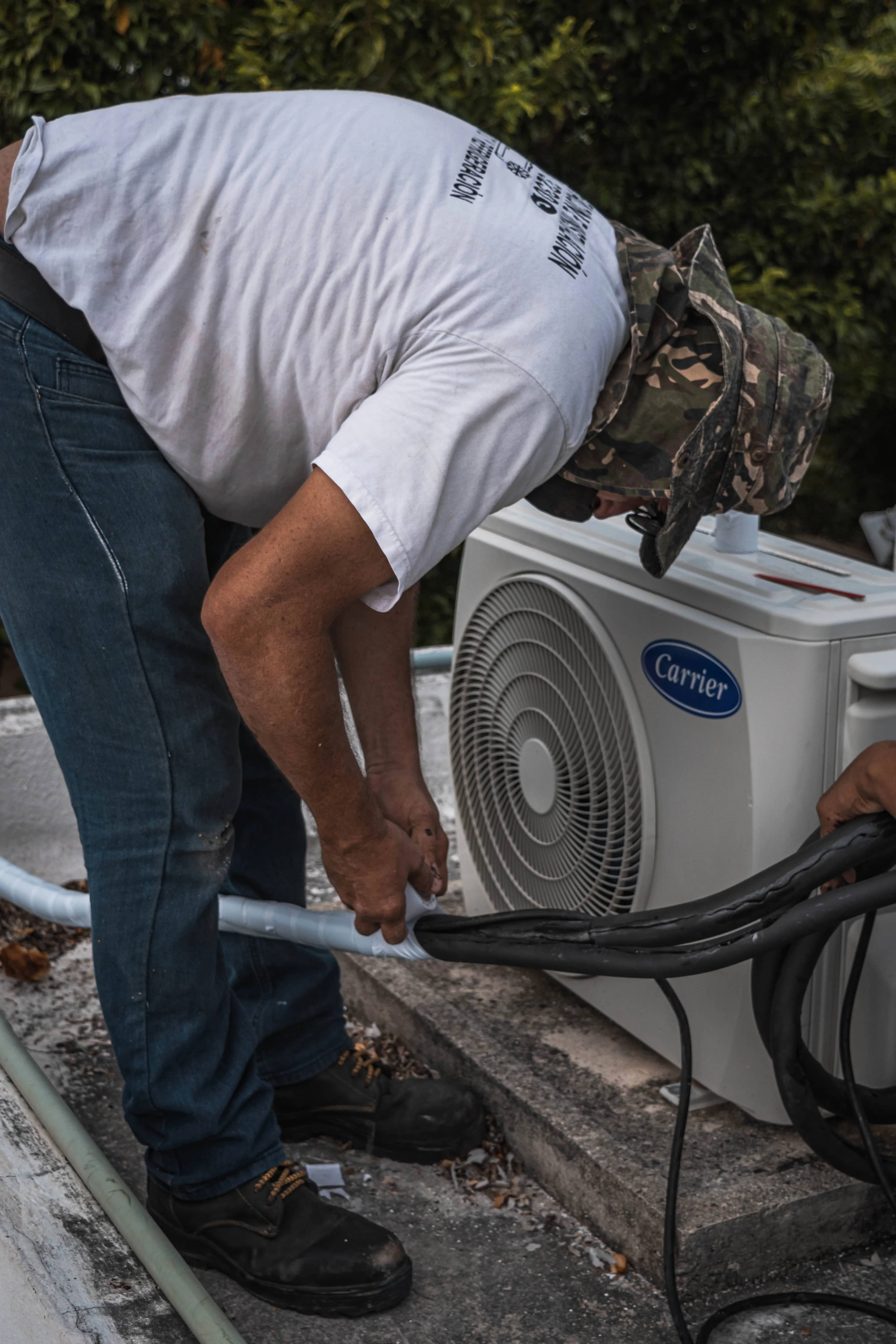 Technician connecting hoses on an outdoor air conditioning unit